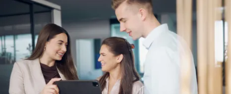 Drei dualer Studentinnen und Studenten tauschen sich an einem Tablet aus.