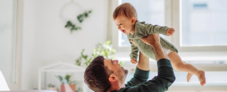 Ein glücklicher Vater hebt sein Baby hoch, dessen Vaterschaft er offiziell anerkannt hat.