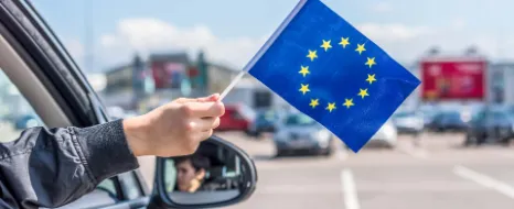 Person hält kleine EU-Fahne aus dem Autofenster.