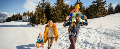Eine Familie genießt ihren Skiurlaub und wandert mit einem Schlitten durch den Schnee.
