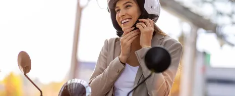 Junge Frau auf Roller lächelt und schließt den Helmgurt