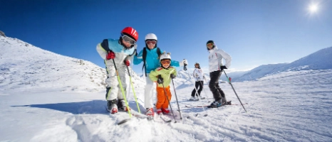 Eine Familie fährt gemeinsam Ski und ist mit passenden Versicherungen für den Skiurlaub abgesichert. 