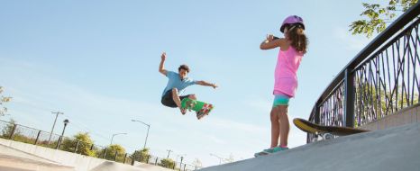 Junges Mädchen mit Vater im Skatepark.
