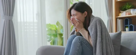 Eine Frau hat eine Allergie und muss in ihrer Wohnung heftig niesen.