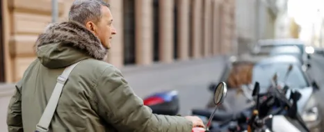 Mann fragt sich, wo er seinen Roller in der Stadt parken darf.