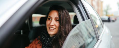 Frau fährt mit geöffnetem Autofenster durch die Stadt.