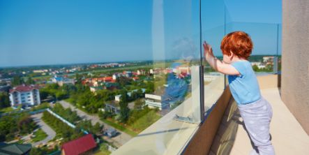 Ein kleiner Junge genießt die Aussicht auf die Stadt von der Dachterrasse eines mehrstöckigen Gebäudes