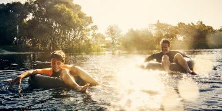 Vater und Sohn im Fluss auf Schwimmreifen.