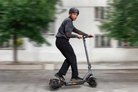 Junger Mann fährt auf seinem E-Scooter und beide sind gut versichert.