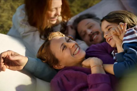 Glückliche Familie mit 2 Kindern tobt im Garten 