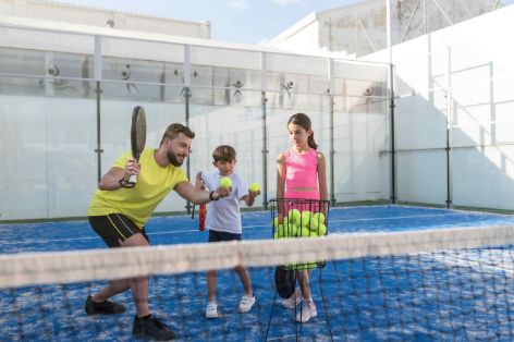 Ein Vater spielt mit seinen Kindern Padel-Tennis.