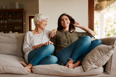 Eine Oma umgeben von ihrer Enkelin auf der Couch sprechen über das Sparen für Kinder
