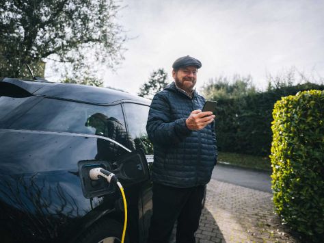 Mann lädt sein E-Aut auf.
