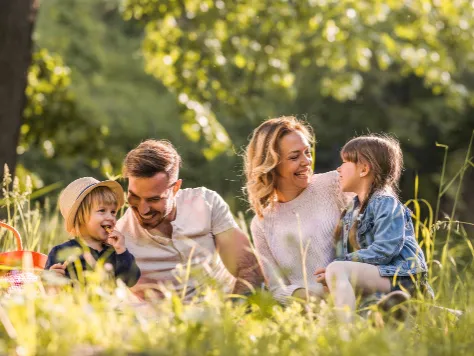 Eine fröhliche Familie macht ein Picknick auf der Wiese.