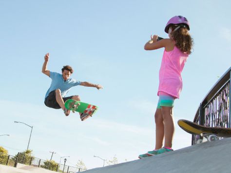 Junges Mädchen mit Vater im Skatepark.
