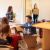 Eine Gruppe von vier Studenten zieht in ihre Wohngemeinschaft ein und beginnt, Kisten auszupacken. Ein männlicher Student sieht seine Kisten im Vordergrund durch.