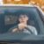 Ein junger Teenager sitzt im Auto und lernt Autofahren.