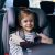 Ein Mädchen sitzt im Auto im Kindersitz und wird angeschnallt.