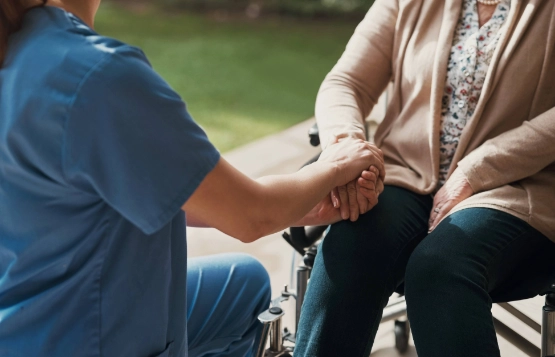 Seniorin im Rollstuhl und Krankenschwester im Freien im Garten