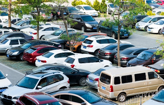 Überfüllter Parkplatz mit zahlreichen Autos unterschiedlicher Farben und Modelle, dicht geparkt nebeneinander