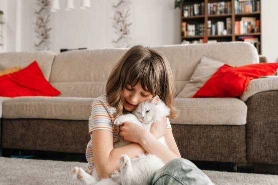 Ein kleines Mädchen kuschelt mit seiner Katze.