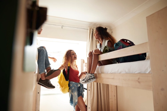 Gruppe von Jugendlichen unterhalten sich im Zimmer einer Jugendherberge