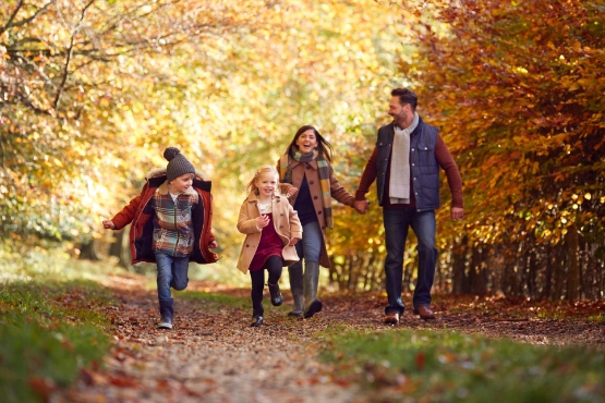 Eine Familie geht gemeinsam im herbstlichen Wald spazieren.