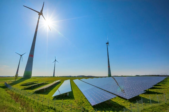 Windkraftanlagen und Solarmodule in grüner Landschaft unter blauem Himmel