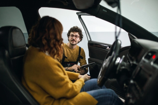 Kfz-Mechaniker berät junge Frau in der Werkstatt.