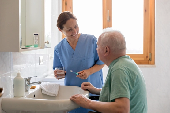 Pflegeperson mit Senior Mann im Badezimmer zu Hause 