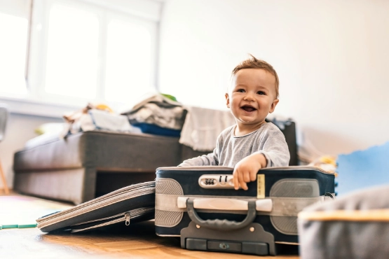Lachender Kleinkind sitzt zwischen Werkzeugen und Bauelementen im hellen Wohnzimmer