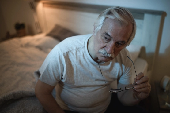 Nachdenklicher Senior Mann im Schlafzimmer in der Nacht auf Bettkante sitzend