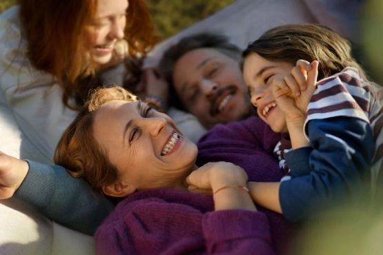 Eine Familie mit zwei Kindern liegt vergnügt in einer Hängematte.