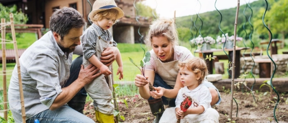 Vierköpfige Familie beim Gärtnern im eigenen Garten – Symbolbild zur Auszeichnung der R+V als familienfreundlichster Versicherer.