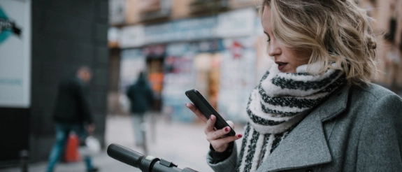Junge Frau fährt mit dem E-Scooter durch die Stadt.