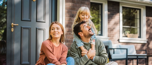Familie sitzt vor der Haustür Ihres Hauses