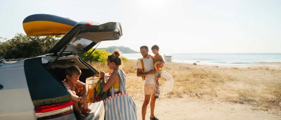 Eine Familie genießt den Urlaub mit dem Auto am Strand.