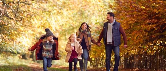 Eine Familie geht gemeinsam im herbstlichen Wald spazieren.
