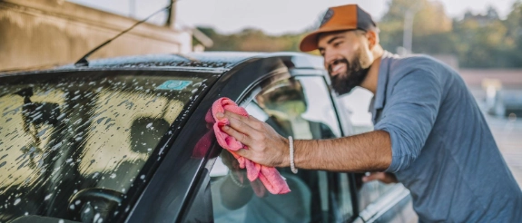 Mann wäscht Auto per Hand.