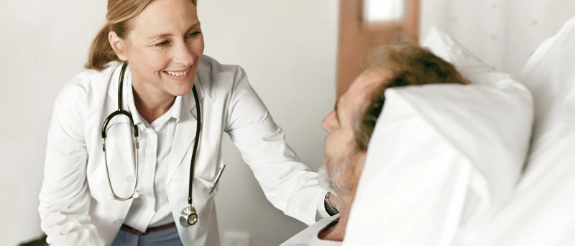 Ärztin mit Stethoskop untersucht Patient im Krankenhaus, freundliche ärztliche Beratung