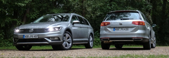Zwei silberne Volkswagen Passat Fahrzeuge parken nebeneinander auf Kiesplatz vor grünem Waldgebiet