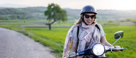Eine Frau fährt nach der Anmeldung glücklich auf ihrem Roller.