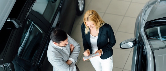 Zwei Personen verhandeln zwischen zwei Autos auf einem Parkplatz, Luftaufnahme