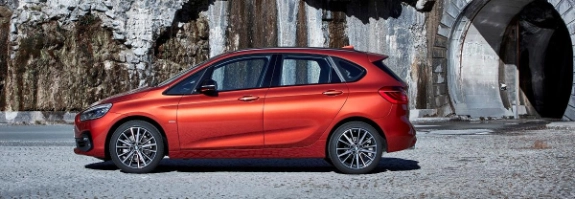 Roter BMW Active Tourer parkt vor dramatischer Felswand mit Eiszapfen und Wasserfällen