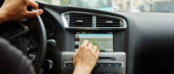 Person bedient Navigationssystem im Auto