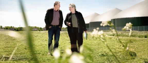 Zwei Geschäftspartner im Gespräch im Freien auf einer Biogasanlage.