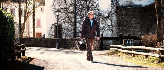 Landarzt mit Arzttasche geht eine Straße entlang.