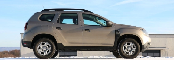 Beiger SUV mit Dachträger auf leerer Straße unter blauem Himmel, Seitenansicht