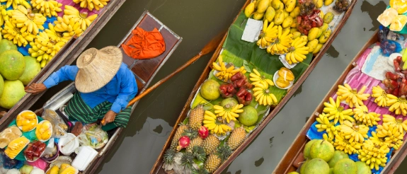 Blumenboote mit bunten Blüten und Blattwerk in Reihen auf dem Wasser nebeneinander.