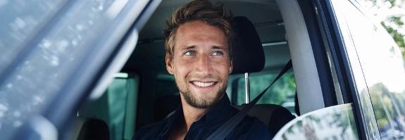 Junger Mann schaut aus dem Auto.